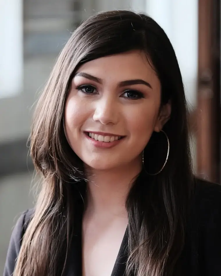 Sandy Wolter smiling, with long dark hair, hoop earrings and a black jacket