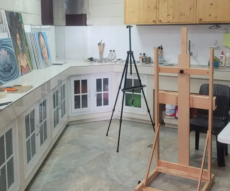 Sandy's studio: a wooden easel and a tripod easel on a stone floor, her canvases leaning against the worktop